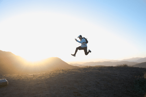 A man jumping in front of a mountain, symbolic jump to personal growth and development plan to transform your life