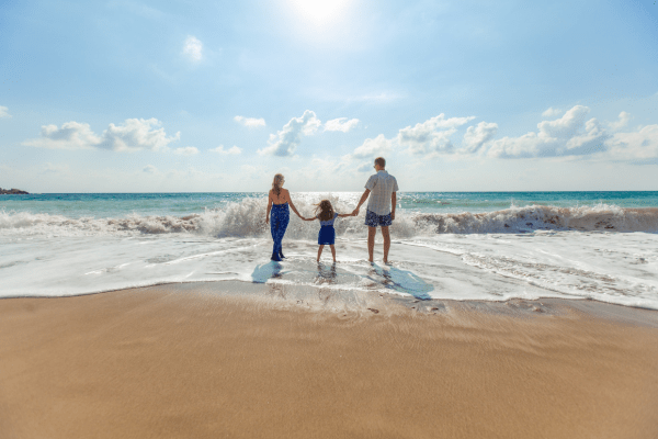 Family staying on the beach and going in the beginning of the sea. This image relates to popular blog post ideas for moms