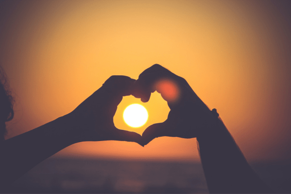 making a heart with the hands during sunset. Blog post in relation to what are self-love affirmations