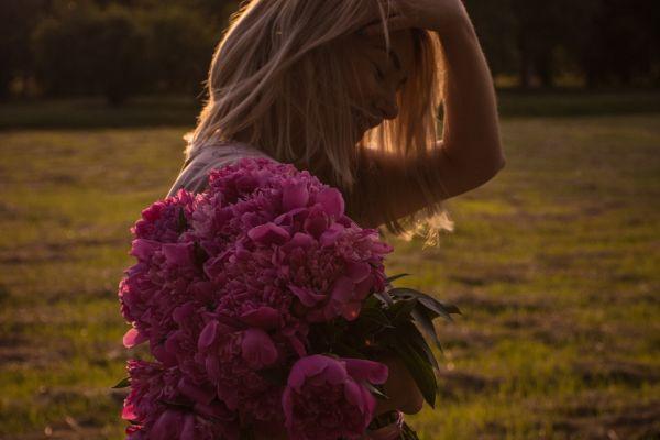photo of a girl holding peonies i relation to a blog post Ways to Romanticize Your Daily Life