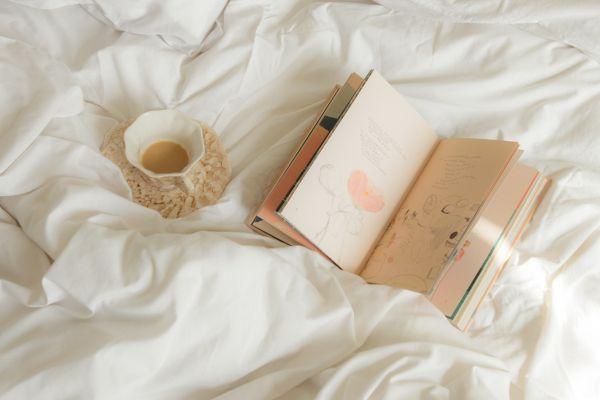 notebook and coffee laying on the bed in relation to sunday motivation quotes