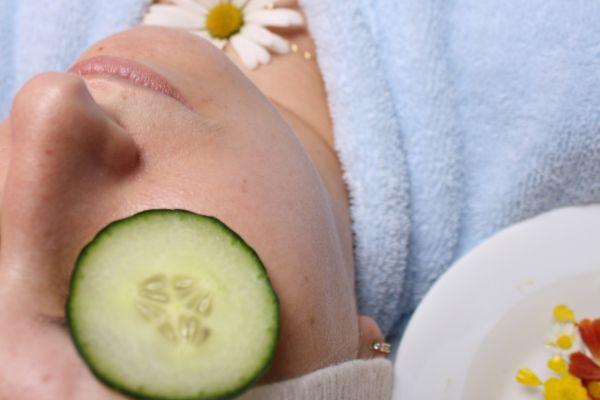 A woman who is relaxing with a face mask and cucumbers in relation to a blog post about what to put in a self care basket-kit-ideas