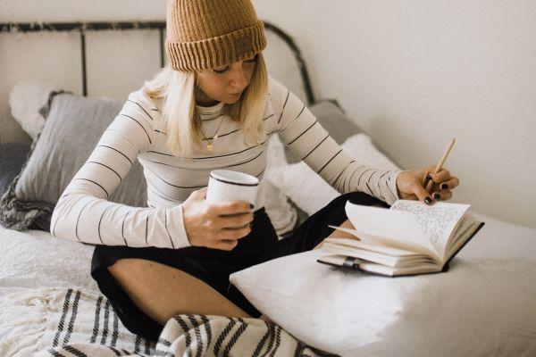 Girl at home writing a blog post in her journal about Things to Do at Home by Yourself