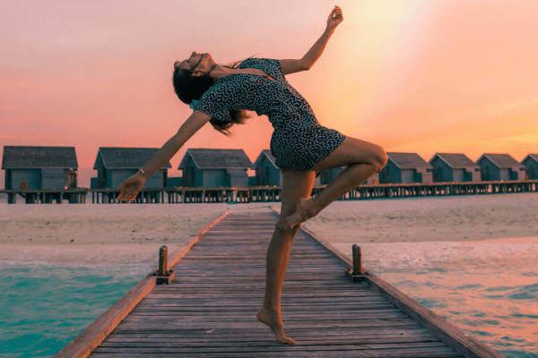 a girl jumping with a beautiful background of a beach. This photo is in relation to a article how to never give up