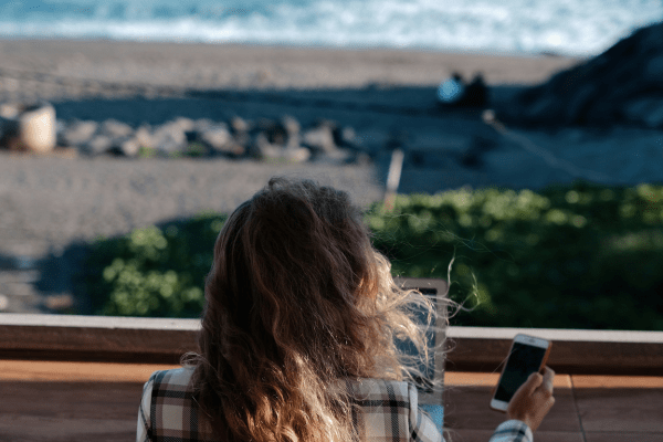 a girl working remotely from the beach. You can see the sea in the background.