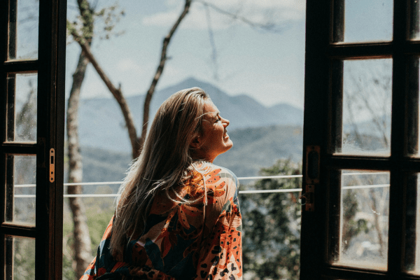 A girl looking through the window and thinking about activities to help you have better self esteem