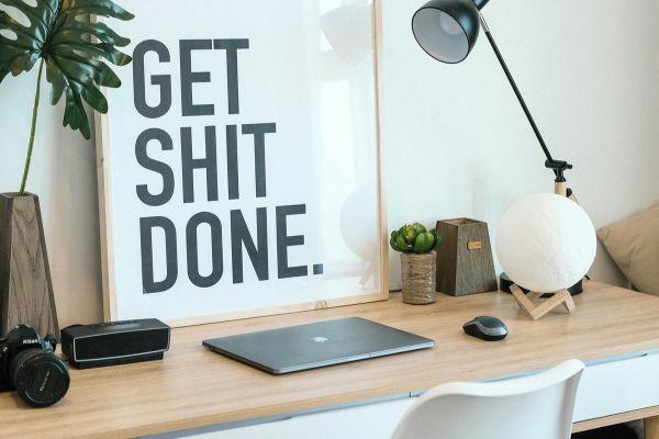 a work desk with motivational poster on how to overcome laziness and procrastination