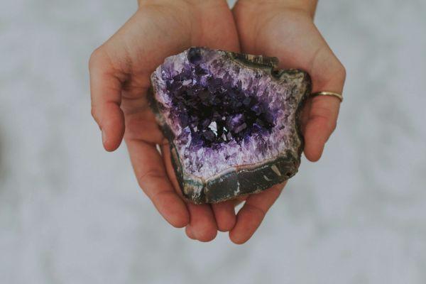 hands holding a healing crystal amethist