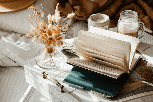 A nice desk over bed with flowers, cup of coffee and a book on how to create an abundance mindset